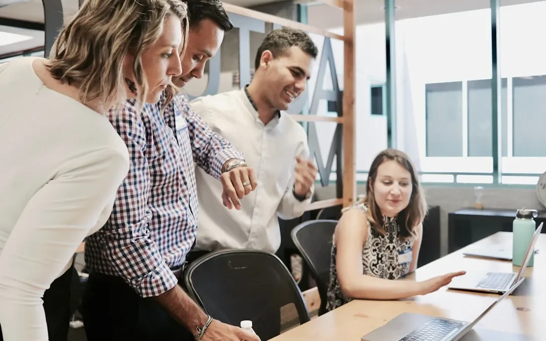 Two colleagues smiling in a bright office as one accepts a compliment from the other