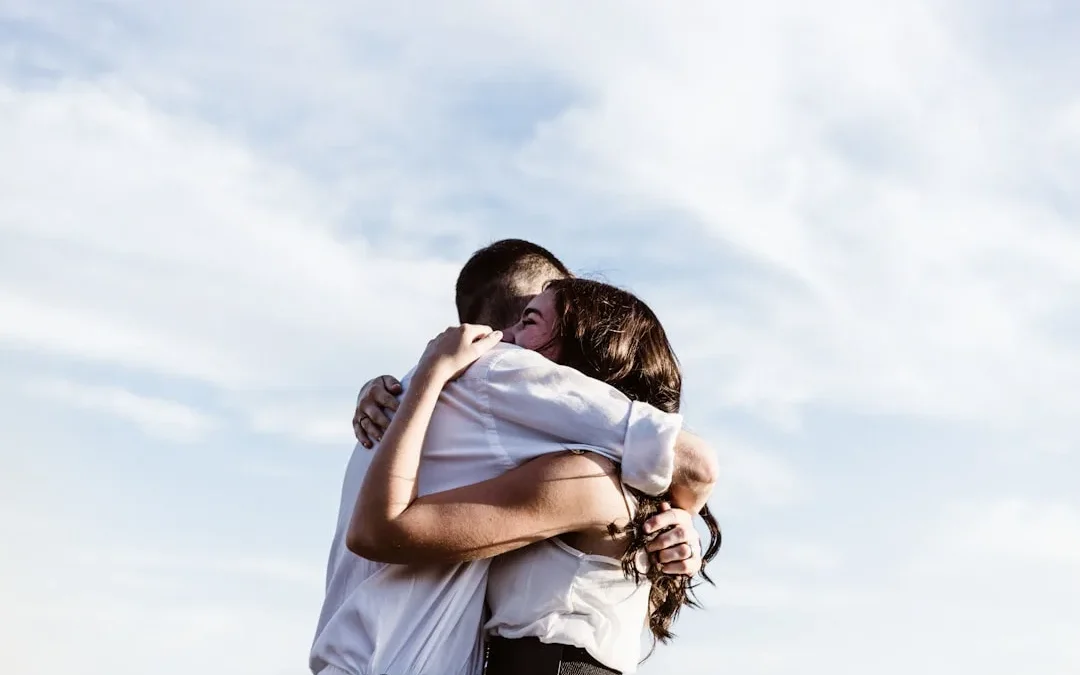 One person warmly reassuring another with a hand on their shoulder during a proud, emotional moment