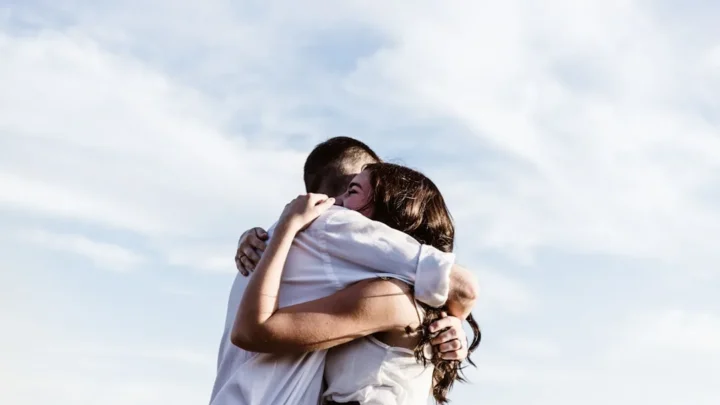 One person warmly reassuring another with a hand on their shoulder during a proud, emotional moment