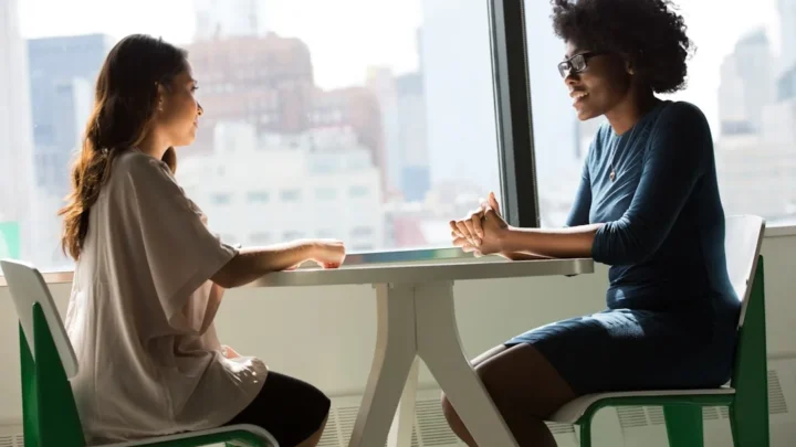 Two people sitting together in an honest conversation, one listening as the other makes amends