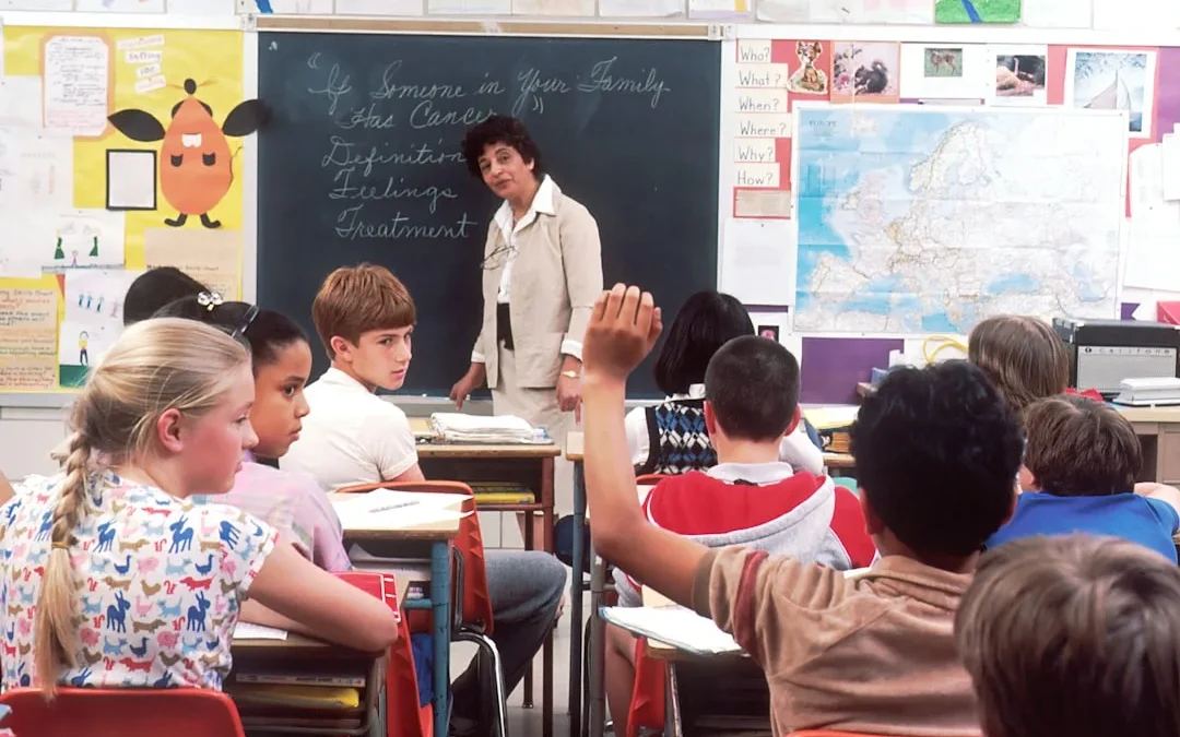 A person raising their hand and answering clearly as their name is called during attendance