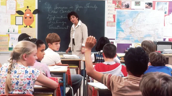 A person raising their hand and answering clearly as their name is called during attendance