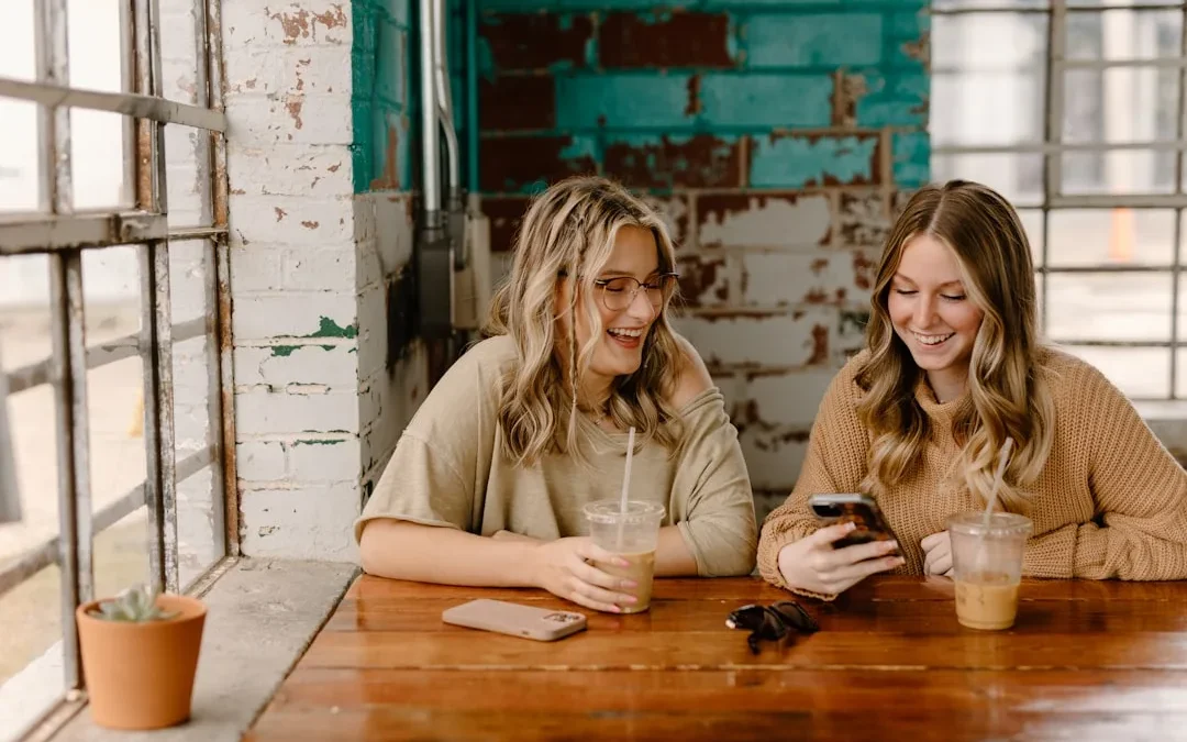 Two friends grinning at a playful text exchange on their phones