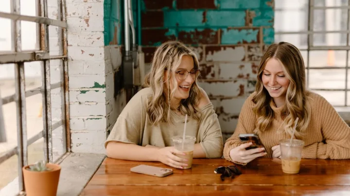 Two friends grinning at a playful text exchange on their phones