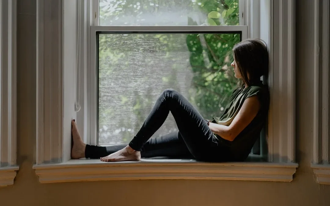 A person sitting quietly by a window, calmly processing a difficult message