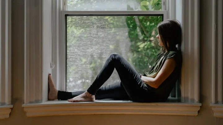 A person sitting quietly by a window, calmly processing a difficult message