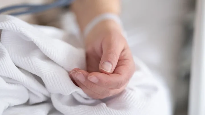 Two hands gently held together, offering quiet comfort at a bedside