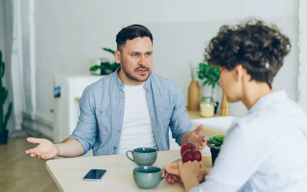 Two people sitting down and calmly talking through a tense disagreement