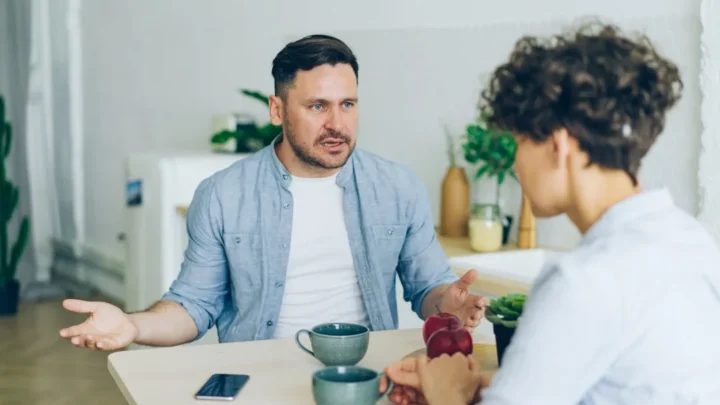 Two people sitting down and calmly talking through a tense disagreement