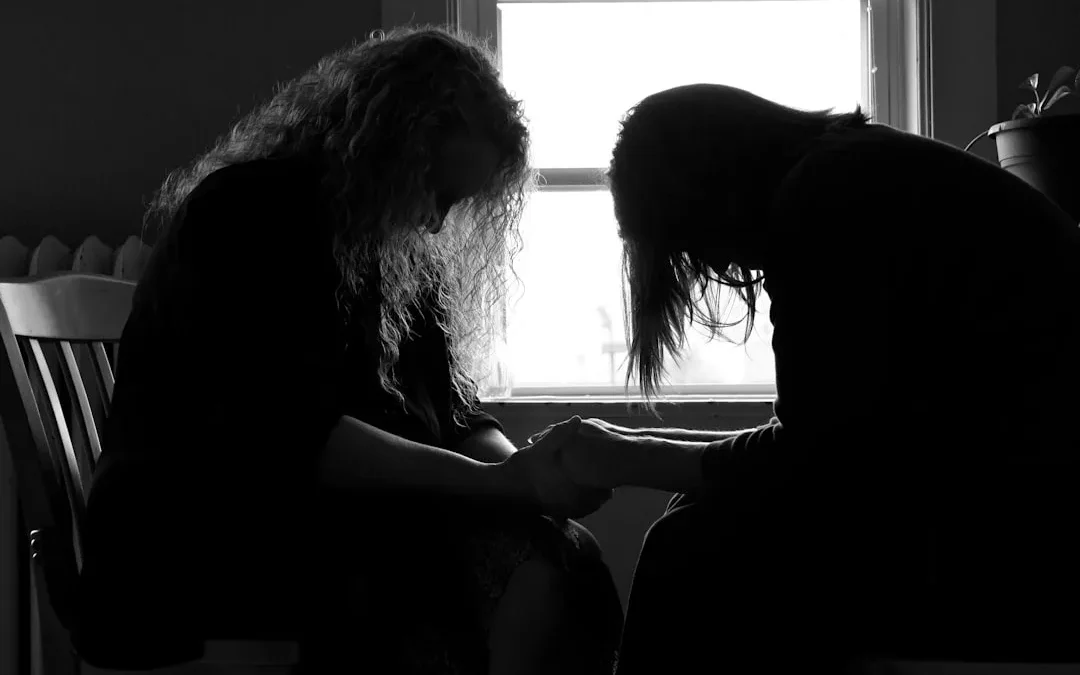 supportive friend sitting beside grieving person in gentle daylight
