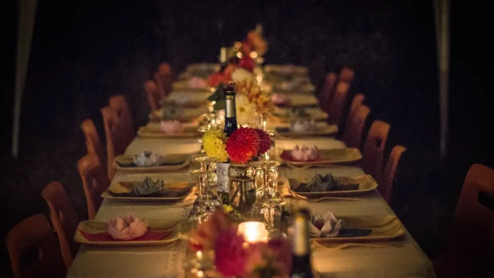 A long dining table set for a dinner party with flowers and candles