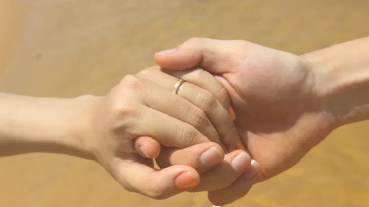 a close up of two people holding hands