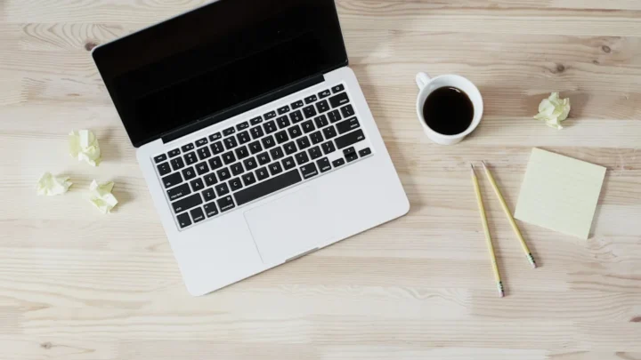 turned off MacBook Pro beside white ceramic mug filled with coffee