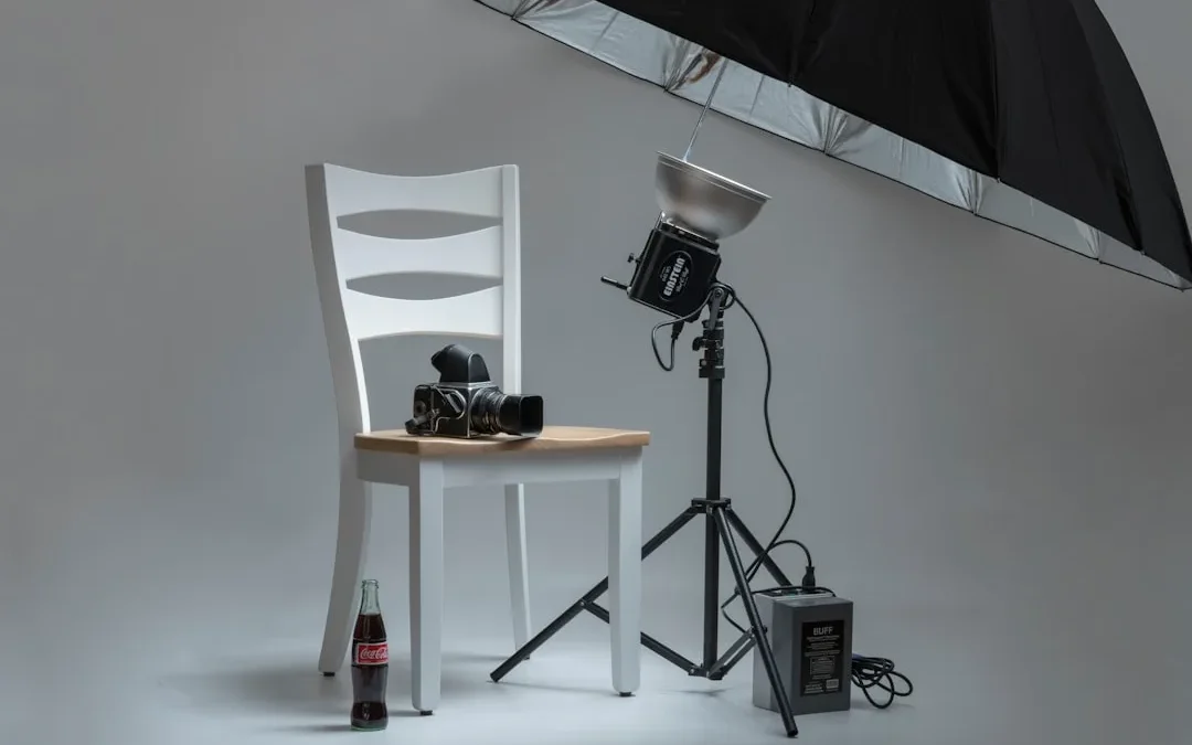 black video camera on white wooden chairs beside photo shooting umbrella