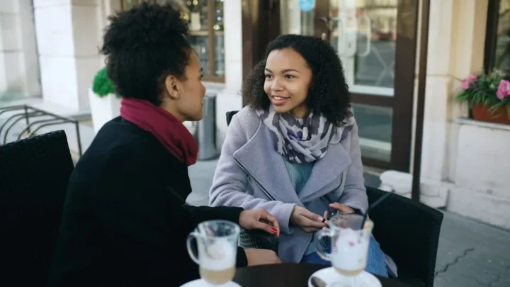 Two women talking at an outdoor cafe table
