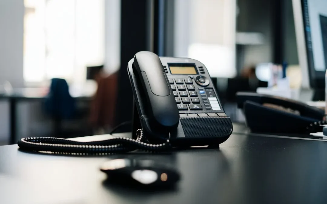 black ip desk phone on black wooden table