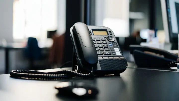 black ip desk phone on black wooden table